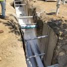 A trench with pipes partially covered by Gilsulate, a white powdery substance